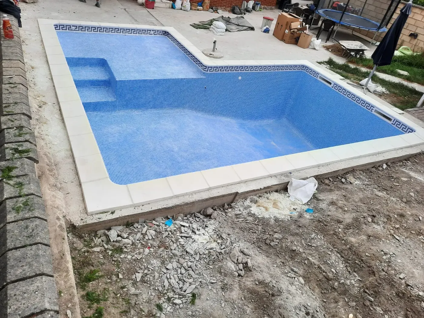 Piscina a medida terminada con alicatado azul y cenefa