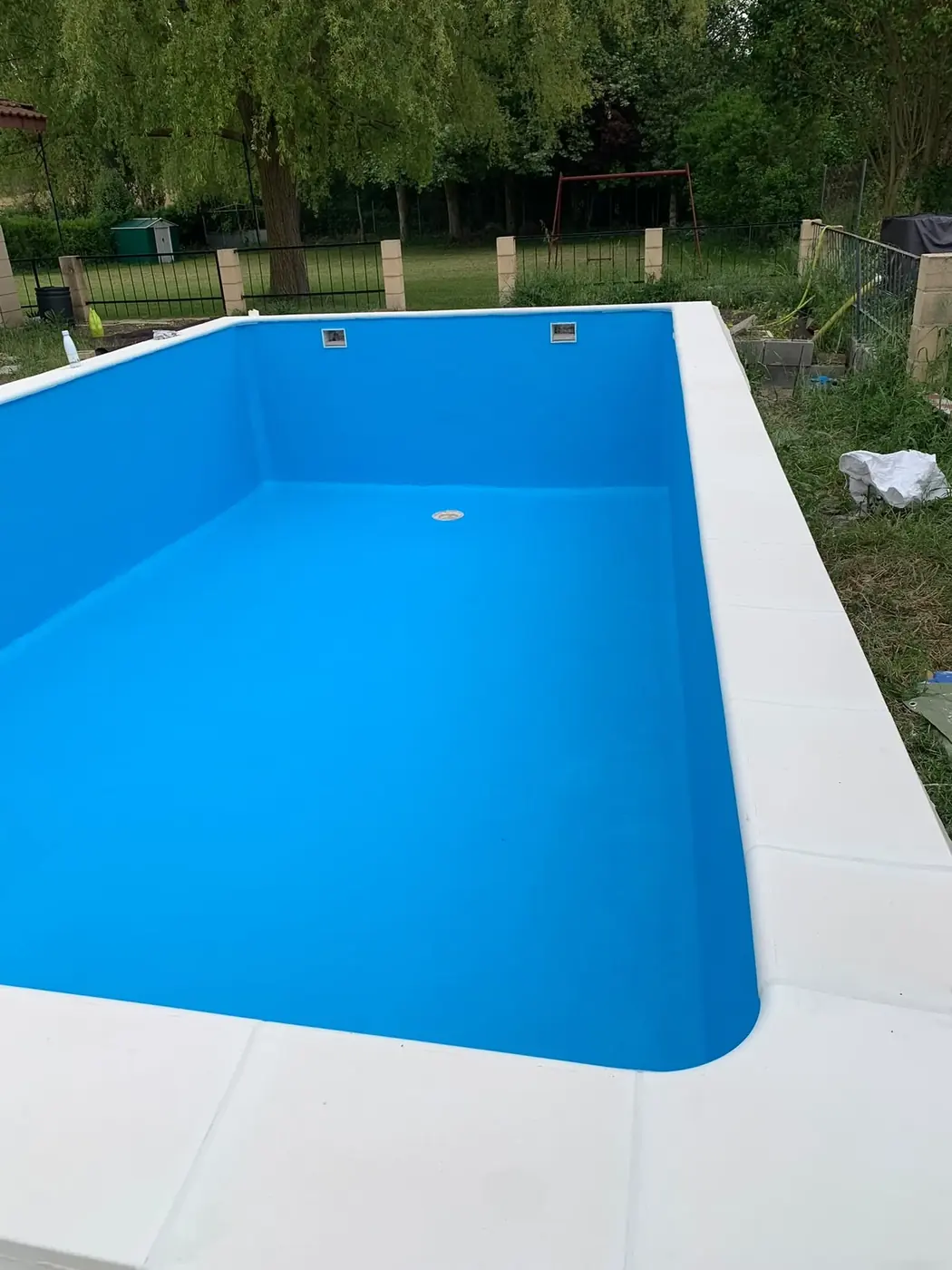 Piscina terminada con liner azul y bordillo blanco