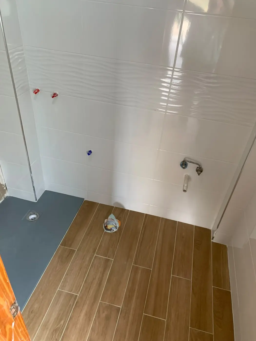 Plato de ducha gris terminado con suelo símil madera