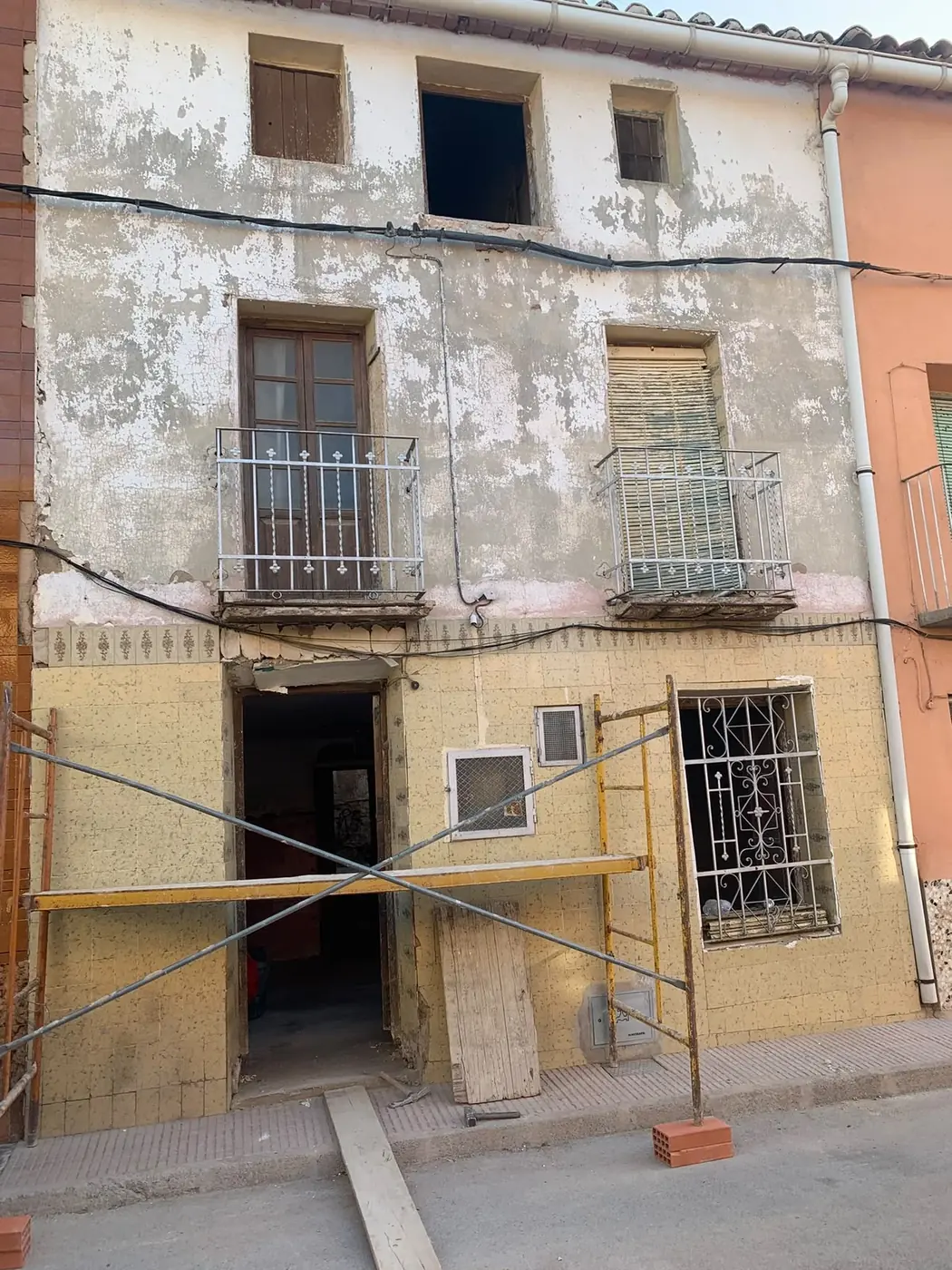 Fachada de pueblo con revoco desconchado y balcones antiguos