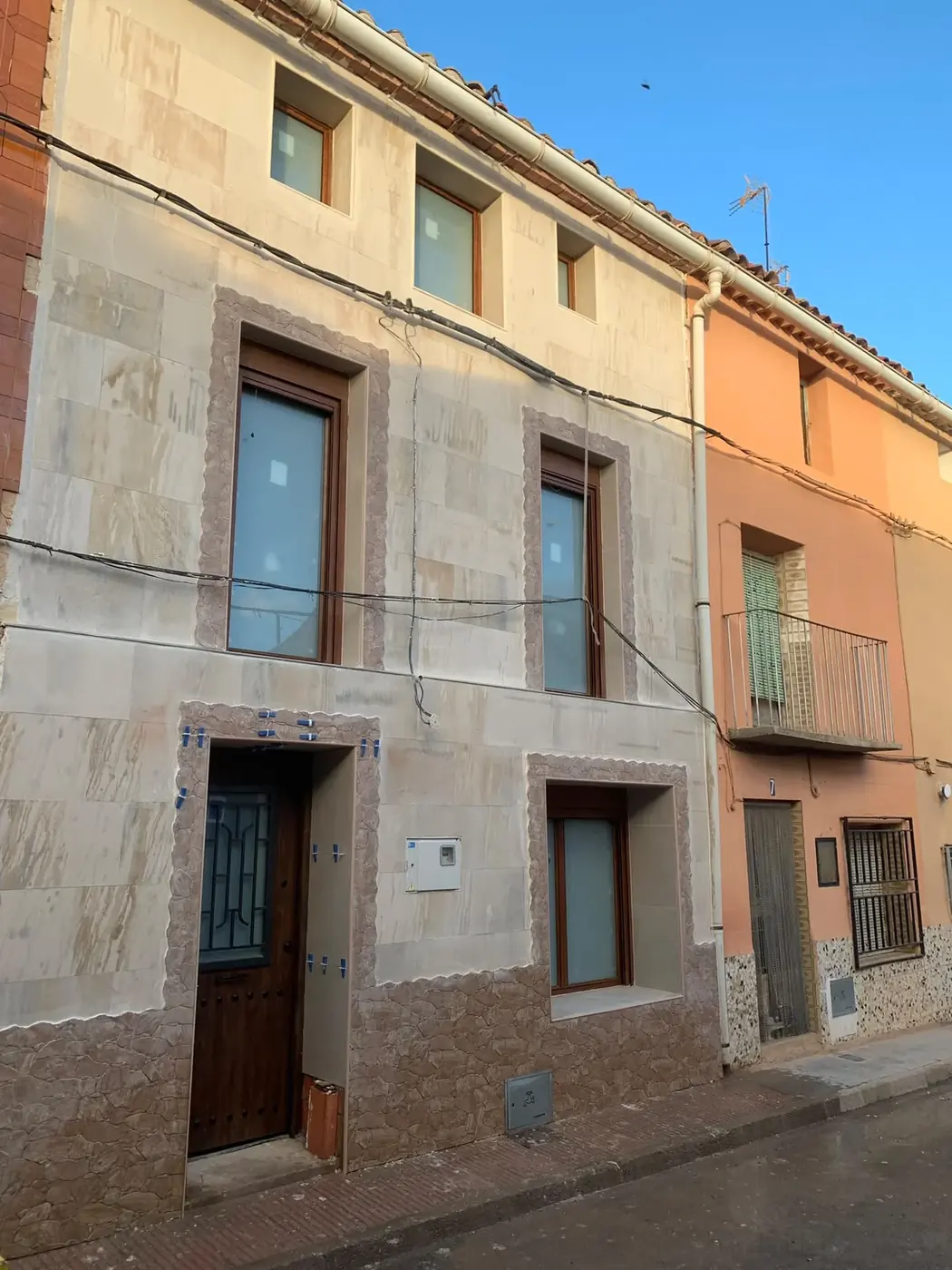 Misma fachada rehabilitada en piedra clara con ventanas nuevas