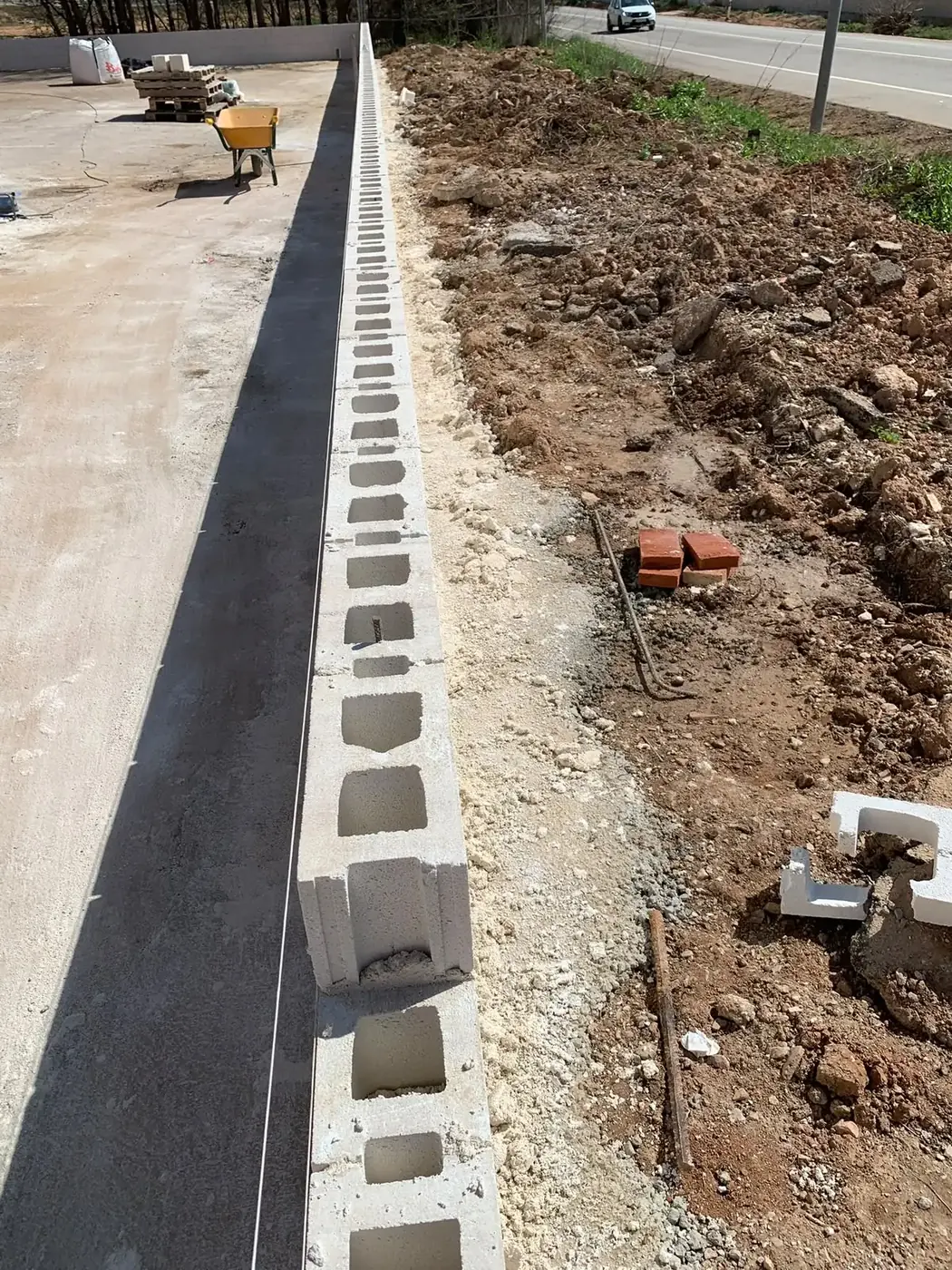 Murete de bloque de hormigón recién levantado junto a una carretera